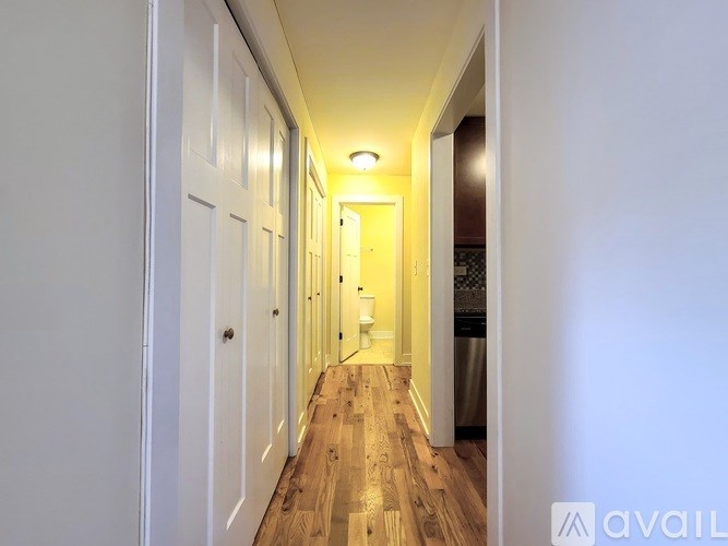 A long hallway with white doors and wooden floors.