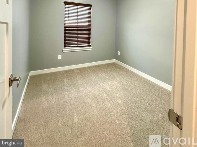 A room with a carpeted floor and a window with blinds.