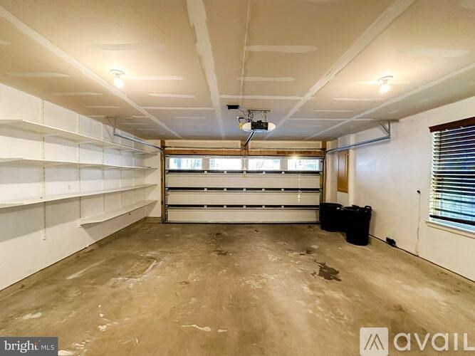 A spacious empty room with a window and a door on the right side.