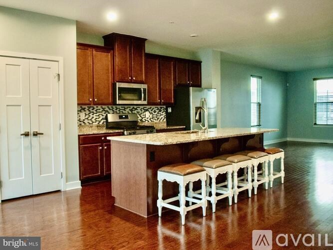 A kitchen with a long island and bar stools.