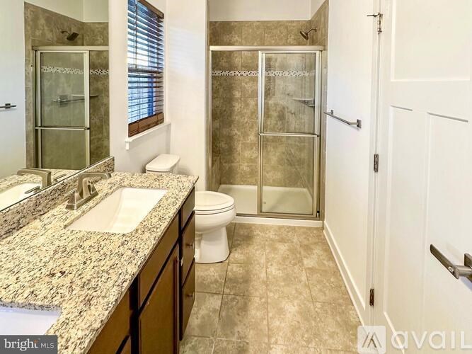 A bathroom with a marble countertop and a walk-in shower.