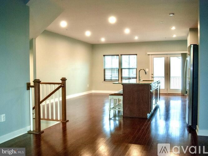 A spacious living room with wood flooring and a staircase with a railing.
