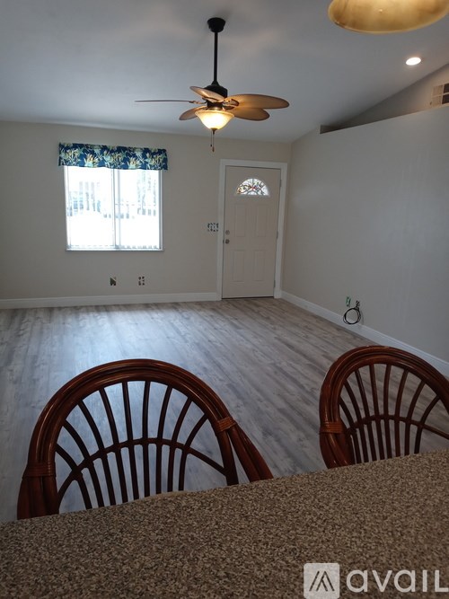 Two chairs are in front of a table in a room with a ceiling fan.