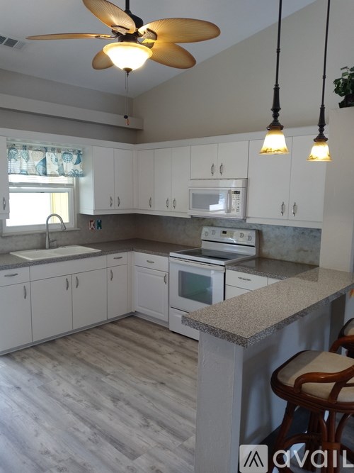 A kitchen with white cabinets and a ceiling fan.