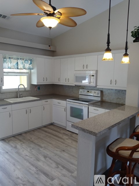 A kitchen with white cabinets and a ceiling fan.
