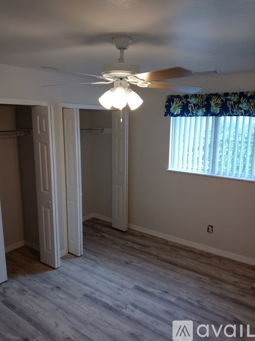 A room with a ceiling fan and a window with curtains.