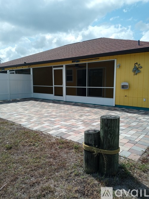 A yellow building with a brown roof and a white fence.