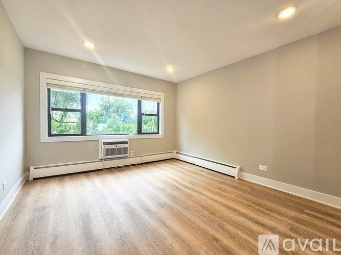 A spacious room with a window and a wooden floor.