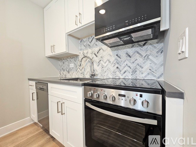 A modern kitchen with a black oven and white cabinets.