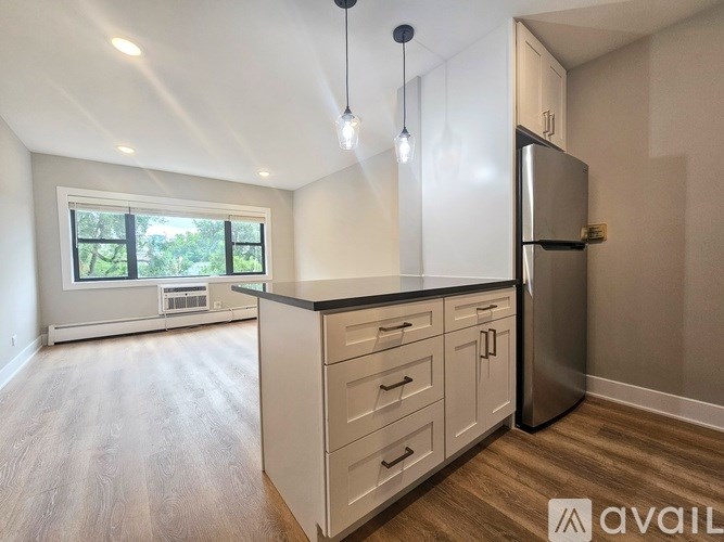 A kitchen with a refrigerator, cabinets, and a window.
