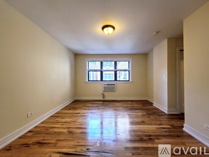 A room with wooden floors and a window with blinds.