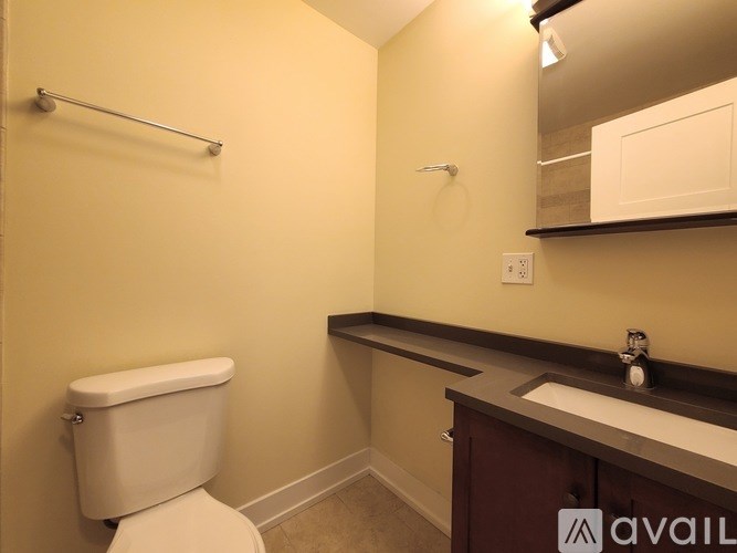 A bathroom with a toilet, sink, and mirror.