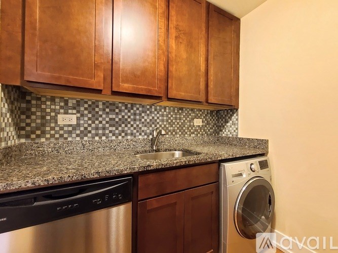 A kitchen with brown cabinets and a black dishwasher.