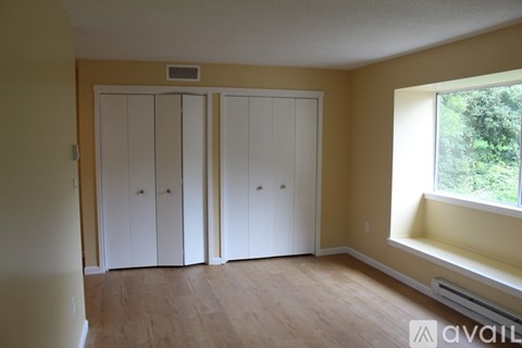 A room with a window and a wall-mounted thermostat.