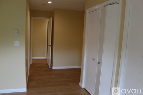 A hallway with a white door on the right and a light switch on the wall.