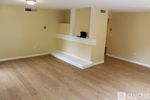 A room with wooden flooring and a white shelf.