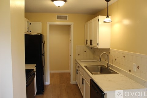 A kitchen with a black refrigerator and white cabinets.