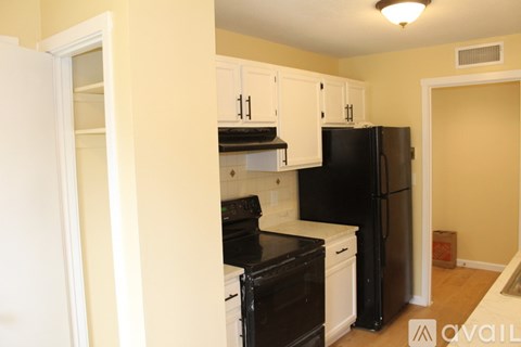 A kitchen with black appliances and white cabinets.