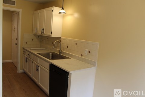 A kitchen with a black dishwasher and white cabinets.