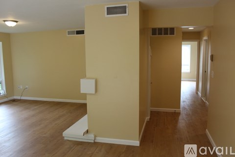 A room with wooden floors and beige walls with a window on the left side.