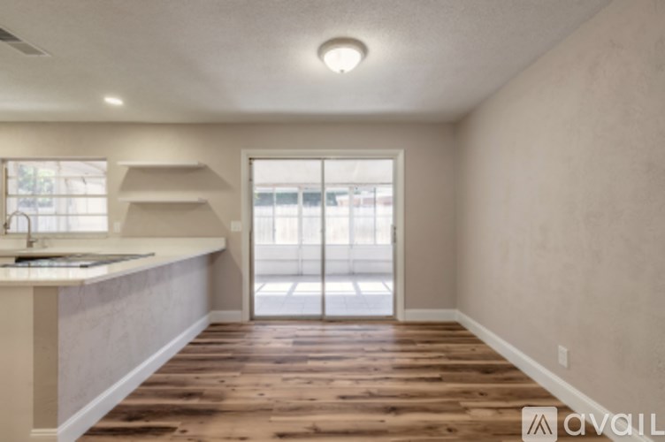A room with wooden floors and a window overlooking a parking lot.