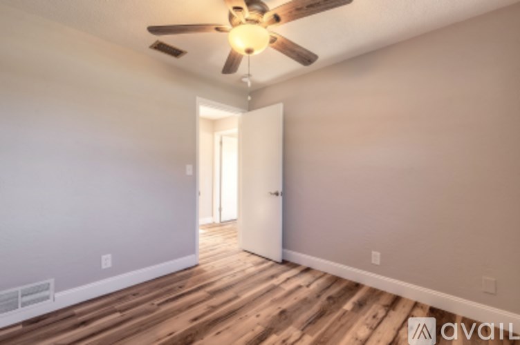 A room with a ceiling fan and wooden flooring.