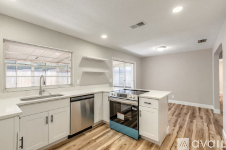 A kitchen with white cabinets and a wooden floor.
