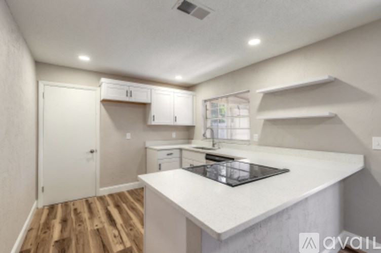 A kitchen with a white countertop and wooden floors.