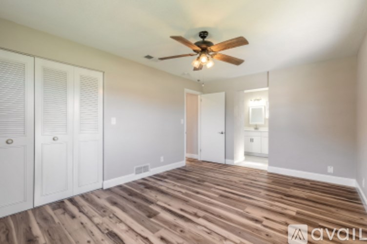 A room with a ceiling fan and wooden flooring.