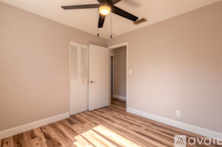 A room with a ceiling fan and wooden flooring.