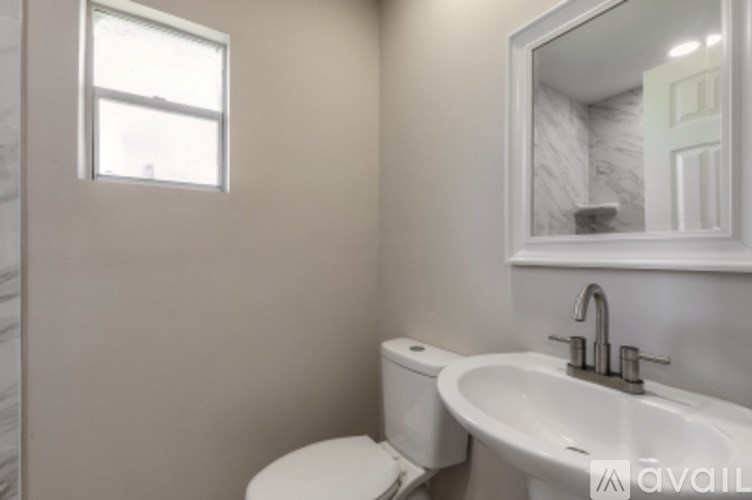 A bathroom with a toilet, sink, and mirror.