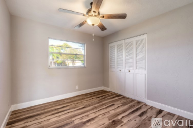 A room with a ceiling fan and wooden flooring.