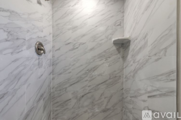 A bathroom with a marble wall and a silver faucet.