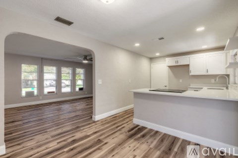 A kitchen with wooden floors and white cabinets is available.