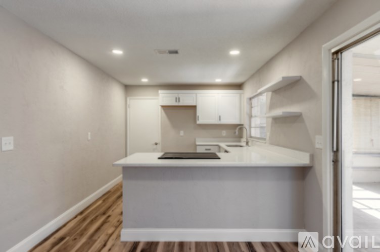 A kitchen with a white countertop and wooden flooring.