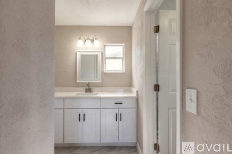 A bathroom with a sink, mirror, and cabinets.