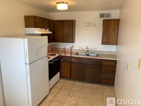A kitchen with a white refrigerator and brown cabinets.