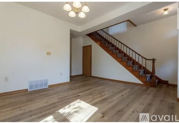 A spacious room with wooden floors and a staircase.