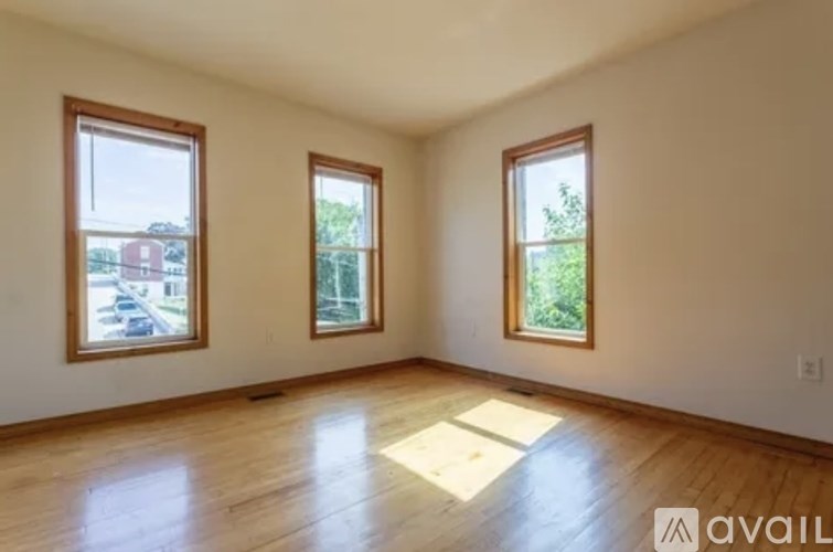 A room with wooden floors and three windows.