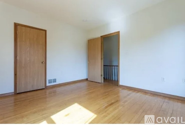 A room with wooden floors and two doors, one of which is open.