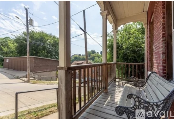 A porch with a bench and a metal railing.