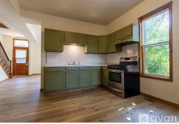 A kitchen with green cabinets and a black stove top oven.