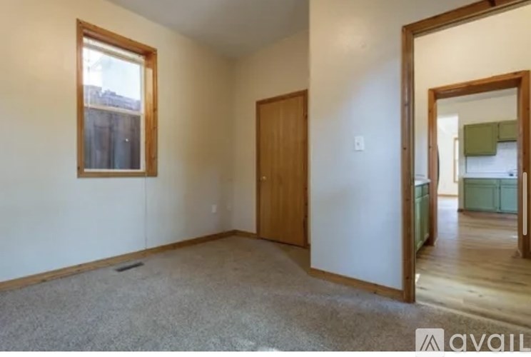 A room with a carpeted floor, a door, and a window.