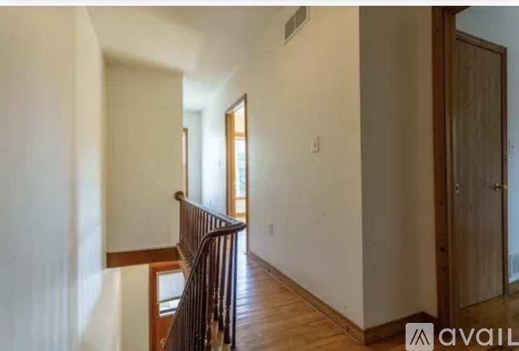 A hallway with a wooden railing and a door on the right.