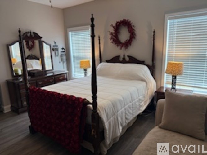 A bedroom with a four poster bed and a wreath on the wall.