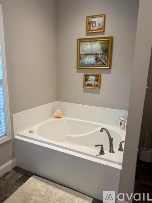 A bathroom with a white tub and three pictures on the wall.