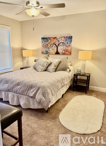 A bedroom with a bed, two lamps, and a painting on the wall.