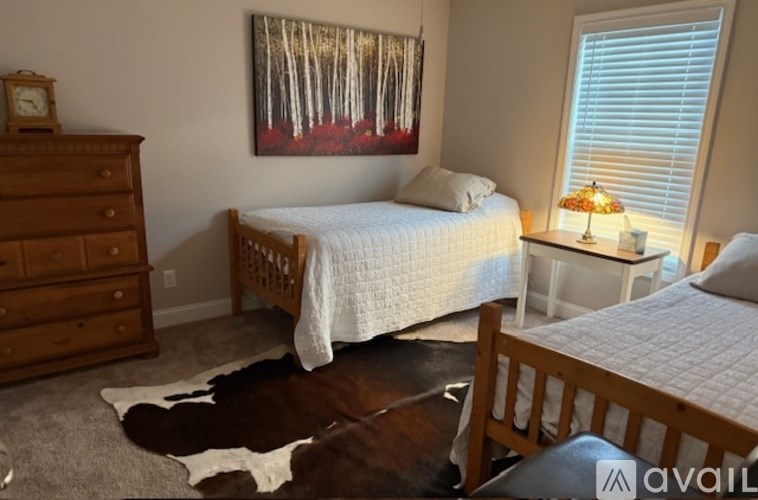 A bedroom with a bed, dresser, and a painting on the wall.