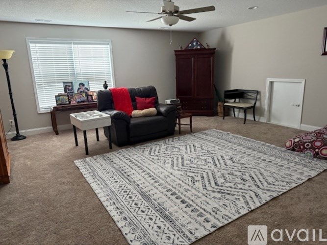 A living room with a black couch, a white coffee table, and a rug on the floor.