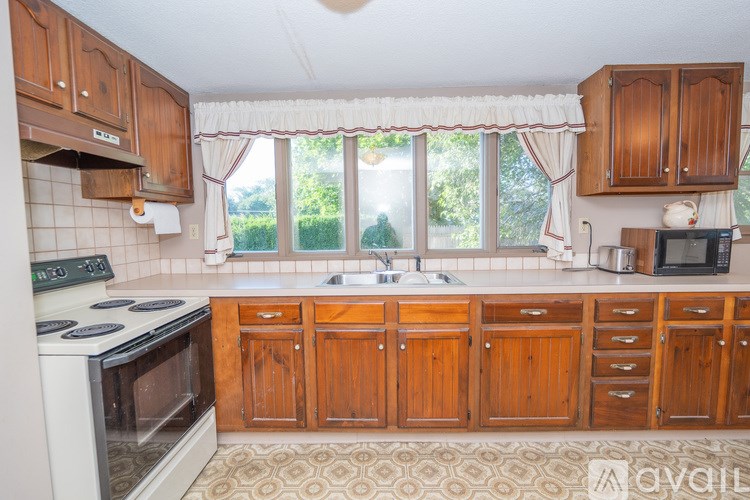 A kitchen with wooden cabinets and a white stove top oven.